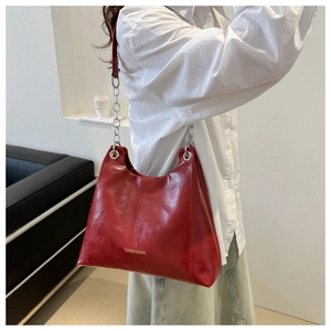 Dettaglio borsa a spalla in pelle rossa con scritta dorata e tracolla a catena d'argento
