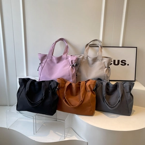 Cinq sacs cabas en nylon imperméable avec cordons latéraux sur un support blanc minimaliste