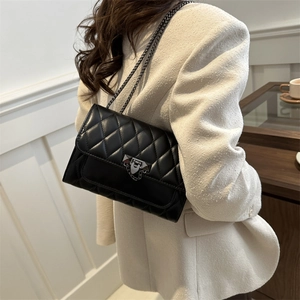 Quilted crossbody bag with chain strap and metal lock shown on a model in a room