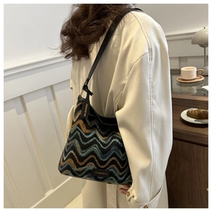 Close-up of stylish tricolor woven bucket bag with elegant chevron pattern and leather strap