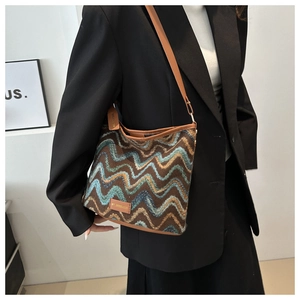 Detail of the woven shoulder bag featuring a bohemian wave pattern and leather trim
