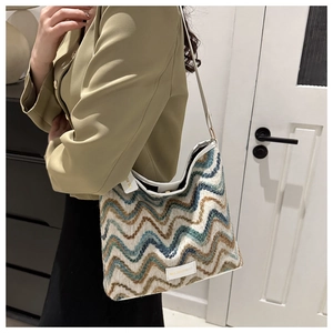 Detail of multi-color woven bucket bag with wavy pattern and white leather shoulder strap