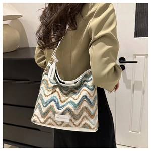 Detail of knitted shoulder bag with blue wavy pattern and leather MS.HUIXIBAG brand tag