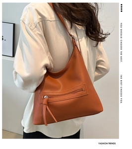 Detail of caramel lychee grain shoulder bag featuring a zip pocket with fringe tassel