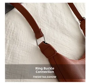Close-up of metal ring buckle connection on brown pebble leather shoulder bag