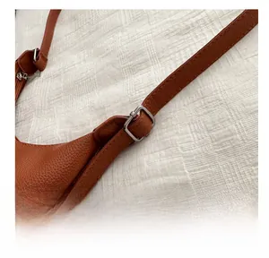 Detail of brown litchi pattern leather tote bag with adjustable silver metal buckle