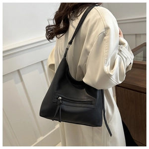 Detail shot of a black pebbled leather hobo bag with a stylish long tassel zipper on a shoulder