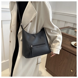 Close-up of black lychee grain tote bag with long tassel zippers and silver hardware