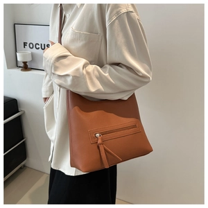 Detail of caramel leather shoulder bag showing lychee grain texture and zipper pocket