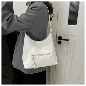 Close-up of white pebble leather hobo bag with zip pocket and long tassel detail