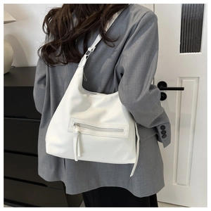 Detailed view of white lychee leather tote bag with side zipper and tassel accents