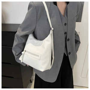Close-up of white hobo bag showing lychee grain leather texture and zipper with fringe tassel