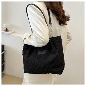 Detail of black tote bag featuring textured pleated fabric and silver chain strap connectors