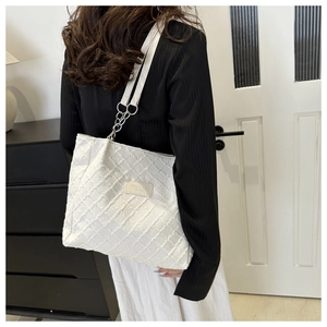 White tote bag with textured checkerboard pattern and chain strap shown on a model