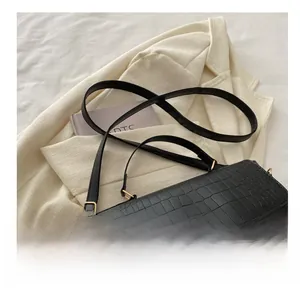 Détail d'un sac à main noir avec texture crocodile et boucle en métal doré chic