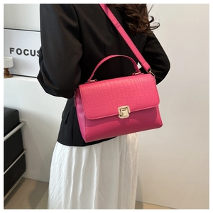 Sac à main rose fuchsia avec texture crocodile et fermoir doré porté à l'épaule