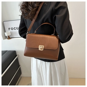 Détail du sac à main marron café avec texture crocodile, fermoir doré et poignée chic