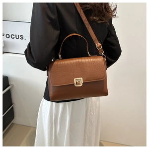 Sac marron gaufré crocodile avec boucle en métal et bandoulière réglable porté par le modèle