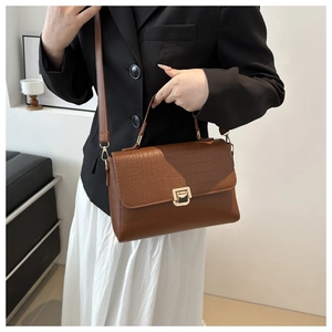 Détail du sac à bandoulière marron foncé élégant avec texture croco et fermoir doré