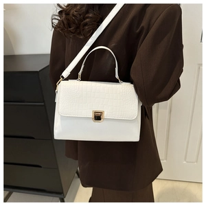 Détail d'un sac à main blanc avec texture crocodile et fermoir en métal doré chic