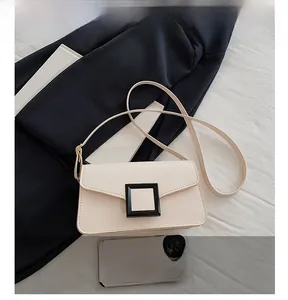 Detail view of cream PU leather shoulder bag with resin buckle beside a smartphone