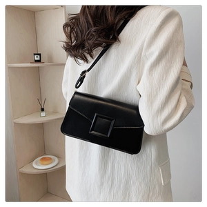 Detail of black minimalist square crossbody bag with large tonal buckle on white blazer