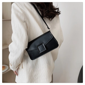 Close-up detail of a black faux leather underarm bag with a matte square buckle and sleek texture