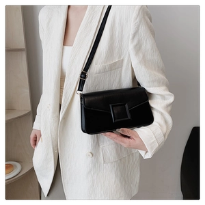 Detail of a black square crossbody bag with large buckle on white textured blazer