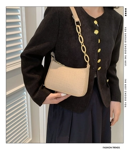 Detail of beige crocodile pattern baguette bag with chunky gold chain shoulder strap