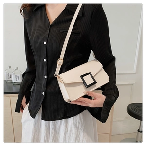 Detail of a chic cream rectangular crossbody bag featuring a bold black square buckle
