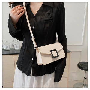 Close-up of cream square crossbody bag featuring a bold black buckle and leather strap