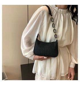 Detail of crocodile embossed leather underarm bag with unique resin link strap worn by model