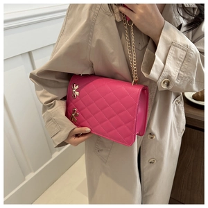 Detail of fuchsia quilted crossbody bag with golden butterfly buckles and chain strap