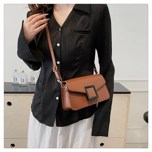 Detailed view of a vintage brown leather crossbody bag with a square buckle on a model