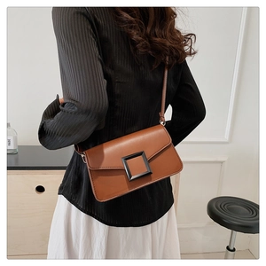 Detailed back view of a brown leather crossbody bag with a square buckle on model