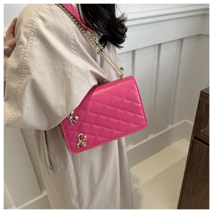 Detail of fuchsia quilted PU leather shoulder bag with gold bow buckles and chain strap