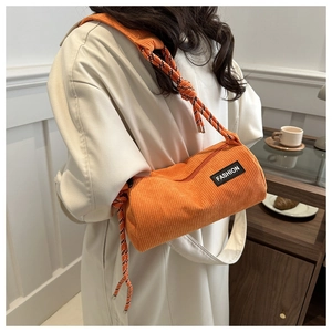 Close-up of orange corduroy cylindrical crossbody bag with woven rope shoulder strap