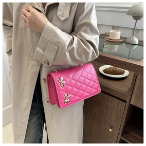Detail of pink quilted crossbody bag with silver butterfly buckles and metal chain strap