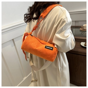 Close-up of orange corduroy cylinder bag with FASHION patch and colorful rope detail