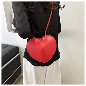 Detail view of red heart-shaped leather crossbody bag with stitching and zipper closure