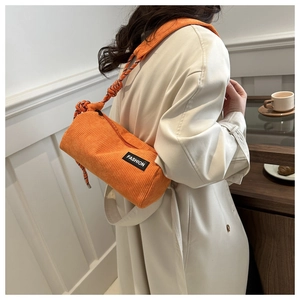 Detail of orange corduroy barrel bag with woven rope strap and fashion label detail