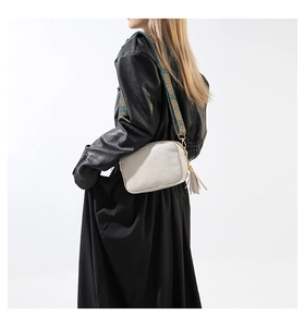 Détail du petit sac carré crème avec bandoulière bohème et pendentif à pompon