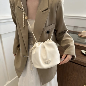 Beige Tunnelzug Beuteltasche mit Goldkette am Modell in einer natürlichen Umgebung