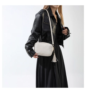 Détail du sac bandoulière carré en cuir blanc cassé avec gland élégant et boucle métallique