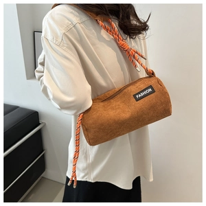 Detail of brown corduroy barrel bag with woven label and orange rope shoulder strap