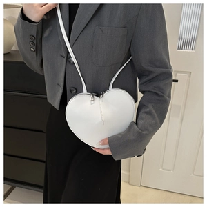Detailed view of a white heart-shaped crossbody bag with silver hardware and smooth finish
