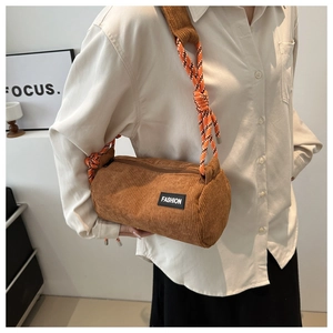 Detail of a brown corduroy cylinder bag featuring a trendy braided rope shoulder strap