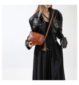 Détail d'un sac bandoulière marron vintage avec franges porté par un mannequin en noir