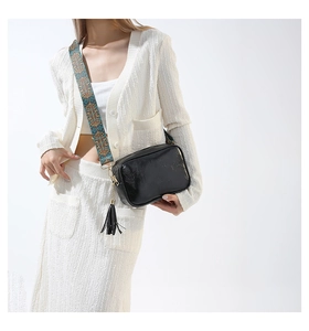 Gros plan du sac bandoulière en cuir noir avec large bandoulière à motif géométrique