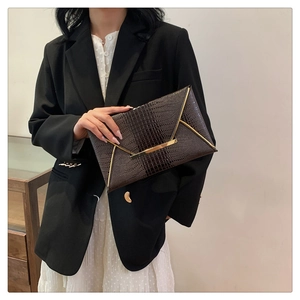 Detail of dark brown crocodile pattern envelope clutch with gold metal V-trim decor